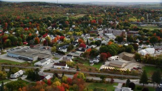 AX150_017 - 5.5K aerial stock footage flying by warehouse and homes, small town, autumn, Winthrop, Maine