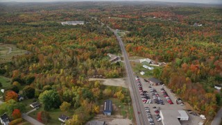 AX150_024 - 5.5K aerial stock footage flying over car dealership, Route 11, colorful foliage in autumn, Winthrop, Maine