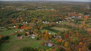 AX150_026E - 5.5K aerial stock footage flying by rural homes, Main Street, colorful foliage, autumn, Monmouth, Maine