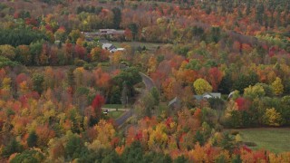 AX150_028 - 5.5K aerial stock footage flying by country road, colorful forest, autumn, Monmouth, Maine