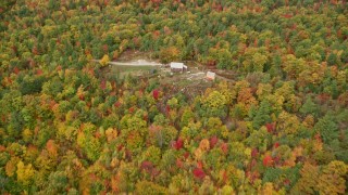 AX150_032E - 5.5K aerial stock footage flying over colorful forest, approach an isolated home, autumn, Leeds, Maine