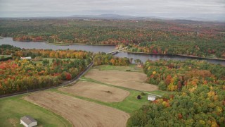 AX150_036E - 5.5K aerial stock footage flying over farm, approach Center Bridge, Androscoggin River, autumn, Leeds, Maine