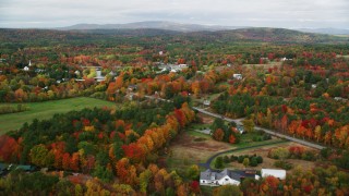 AX150_042 - 5.5K stock footage aerial video flying by a small rural town, colorful foliage in autumn, Turner, Maine