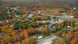 AX150_042E - 5.5K aerial stock footage flying by a small rural town, colorful foliage in autumn, Turner, Maine