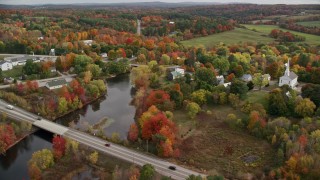 AX150_044E - 5.5K aerial stock footage orbiting a small town, church, colorful foliage in autumn, Turner, Maine