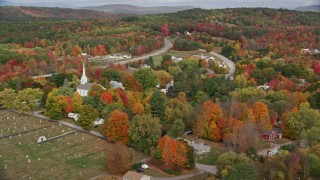 AX150_047 - 5.5K aerial stock footage orbiting church in small rural town, colorful foliage in autumn, Turner, Maine