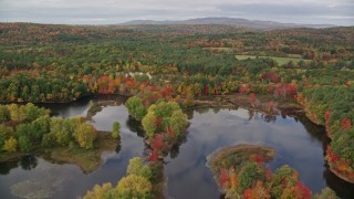 AX150_052 - 5.5K aerial stock footage flying over Nezinscot River, approach colorful forest, autumn, Turner, Maine
