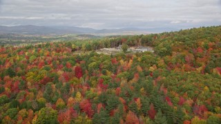 AX150_054E - 5.5K aerial stock footage flying over colorful forest, approaching an isolated home, Turner, Maine