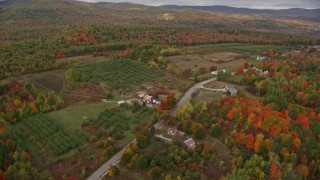 AX150_058 - 5.5K aerial stock footage flying over colorful forest, approaching Hill Road, autumn, Buckfield, Maine