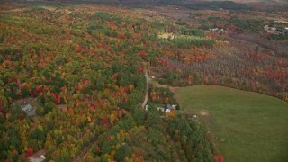 AX150_059E - 5.5K aerial stock footage flying over forest, approach rural homes near South Pond, autumn, Buckfield, Maine