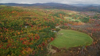 AX150_060 - 5.5K aerial stock footage flying by colorful forest, an isolate homes, autumn, Buckfield, Maine