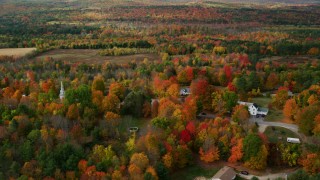 AX150_065 - 5.5K aerial stock footage orbiting small town, rural homes, brightly colored foliage, autumn, Buckfield, Maine