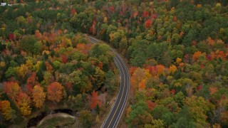 AX150_078E - 5.5K aerial stock footage flying over brightly colored forest, Buckfield Road, autumn, Paris, Maine