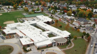 AX150_095 - 5.5K stock footage aerial video approaching Oxford Hills Comprehensive High School, tilt down, autumn, Paris, Maine