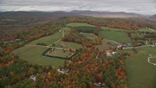 AX150_104E - 5.5K aerial stock footage approaching small farms, colorful trees in autumn, pan right, Norway, Maine