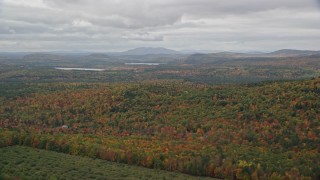 AX150_108E - 5.5K aerial stock footage flying by colorful forest in autumn, overcast, Norway, Maine