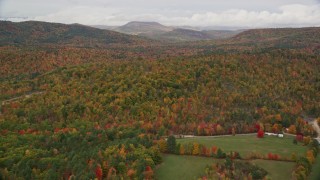 AX150_114E - 5.5K aerial stock footage flying over a brightly colored forest in autumn, overcast, Waterford, Maine