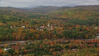 AX150_116E - 5.5K aerial stock footage approaching small rural town, brightly colored forest, autumn, Waterford, Maine