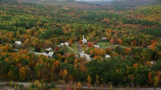 AX150_117 - 5.5K aerial stock footage orbiting small rural town, dense forest in autumn, Waterford, Maine