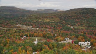 AX150_121 - 5.5K aerial stock footage orbiting small rural town, dense forest, hills, autumn, overcast, Waterford, Maine