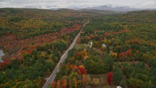 AX150_126E - 5.5K aerial stock footage flying over Maine Street, rural homes, forest, approach small town, Stoneham, Maine