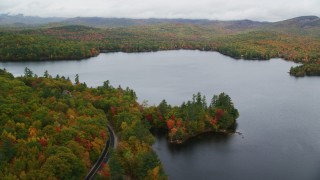 AX150_132 - 5.5K stock footage aerial video flying by Keewaydin Lake, colorful forest, autumn, overcast, Stoneham, Maine