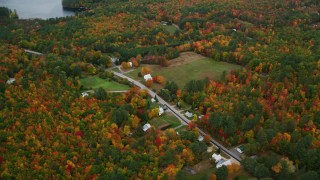 AX150_138 - 5.5K aerial stock footage of a bird's eye view of rural homes, Maine Street, brightly colored trees, autumn, Lovell, Maine
