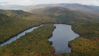 AX150_144 - 5.5K aerial stock footage flying by Horseshoe Pond surrounded by dense forest, autumn, Lovell, Maine