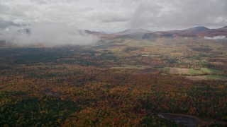 AX150_145E - 5.5K aerial stock footage flying over colorful forest, approach White Mountains, cloudy, autumn, Stow, Maine