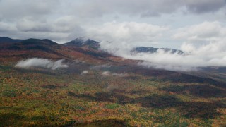 AX150_150 - 5.5K aerial stock footage flying by colorful forest, autumn, cloudy, White Mountains, New Hampshire