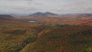 AX150_151E - 5.5K aerial stock footage flying over forest, approaching Mountain Pond, White Mountains, New Hampshire