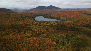 AX150_153 - 5.5K aerial stock footage flying over autumn forest, approach Mountain Pond, White Mountains, New Hampshire