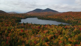 AX150_154 - 5.5K aerial stock footage flying low over forest, autumn, approach Mountain Pond, White Mountains, New Hampshire