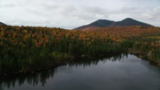 AX150_156 - 5.5K aerial stock footage flying low over Mountain Pond, bright forest, approach White Mountains, New Hampshire