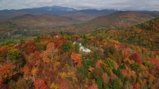 AX150_166 - 5.5K aerial stock footage flying by rural homes, colorful forest, White Mountains, reveal  Jackson, New Hampshire