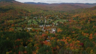 AX150_171 - 5.5K aerial stock footage flying over forest in autumn, approach small town of Jackson, New Hampshire