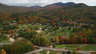 AX150_176 - 5.5K aerial stock footage orbiting Wentworth Golf Club, small town, bordering forest, autumn, Jackson, New Hampshire