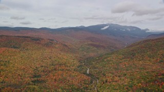 AX150_183 - 5.5K aerial stock footage flying by colorful, dense forest, Mount Washington, overcast, White Mountains, New Hampshire