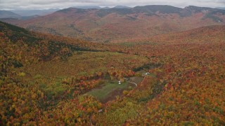 AX150_185E - 5.5K aerial stock footage approaching an isolated home, forest, tilt down, autumn, White Mountains, New Hampshire