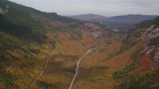 AX150_196E - 5.5K aerial stock footage flying over bright forest, Highway 302, autumn, overcast, White Mountains, New Hampshire