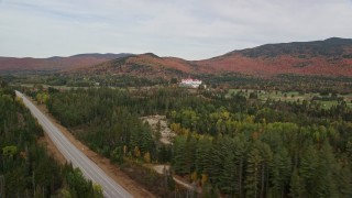 AX150_202E - 5.5K aerial stock footage tilt from highway to reveal Omni Mount Washington Resort, Bretton Woods, autumn, Carroll, New Hampshire
