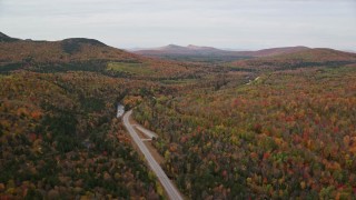 AX150_213E - 5.5K aerial stock footage flying over forest, approach Highway 302, autumn, overcast, Carroll, New Hampshire