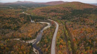 AX150_216 - 5.5K aerial stock footage flying over Highway 302 through forest, autumn, overcast, Carroll, New Hampshire