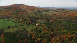 AX150_257 - 5.5K aerial stock footage approaching Pearl Lake Road, tilt down over rural homes, pond, autumn, Lisbon, New Hampshire