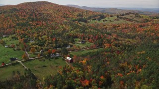AX150_257E - 5.5K aerial stock footage approaching Pearl Lake Road, tilt down over rural homes, pond, autumn, Lisbon, New Hampshire