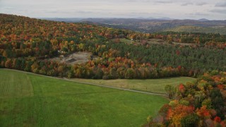 AX150_261E - 5.5K aerial stock footage fly over forest and clearings to reveal an isolated rural home, tilt down, autumn, Lisbon, New Hampshire