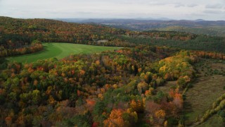 AX150_263 - 5.5K aerial stock footage flying over colorful forest, approach grassy clearing, autumn, Lisbon, New Hampshire