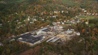 AX150_265 - 5.5K aerial stock footage flying by a factory near river, small town, autumn, Lisbon, New Hampshire