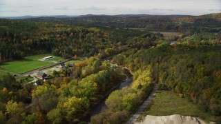 AX150_266 - 5.5K aerial stock footage flying over rural homes, Ammonoosuc River, autumn, Lisbon, New Hampshire