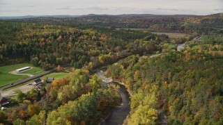 AX150_266E - 5.5K aerial stock footage flying over rural homes, Ammonoosuc River, autumn, Lisbon, New Hampshire